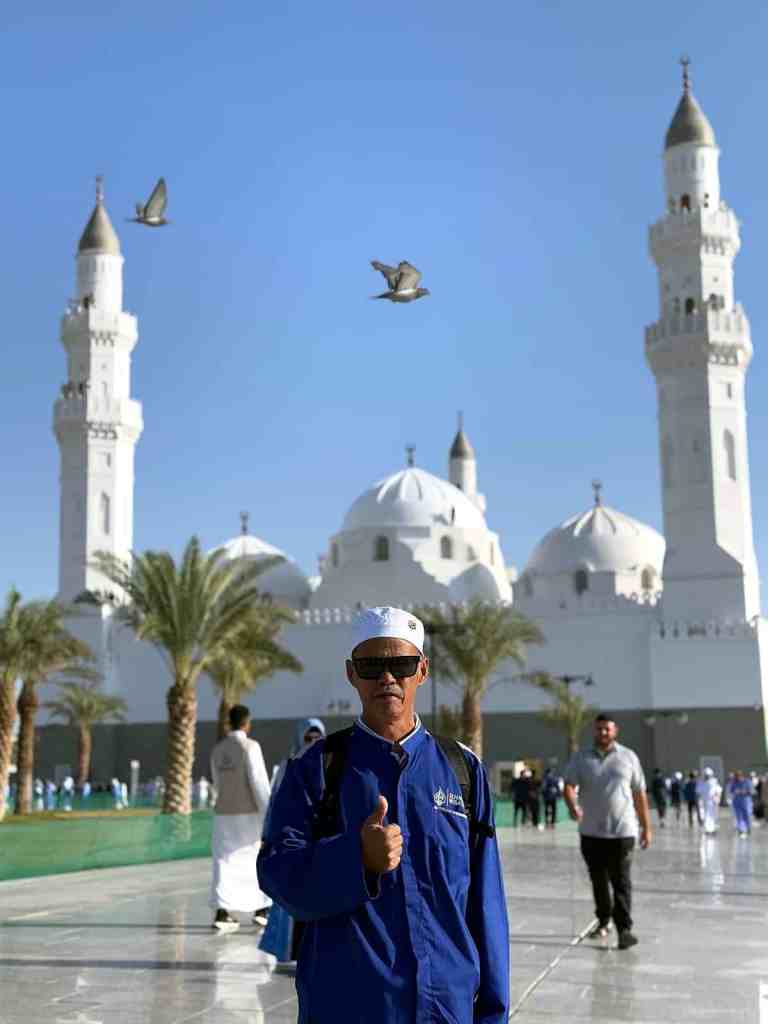 Jamaah haji plus Elharamain Wisata di halaman Masjid Quba Madinah dengan kubah putih dan pohon kurma
