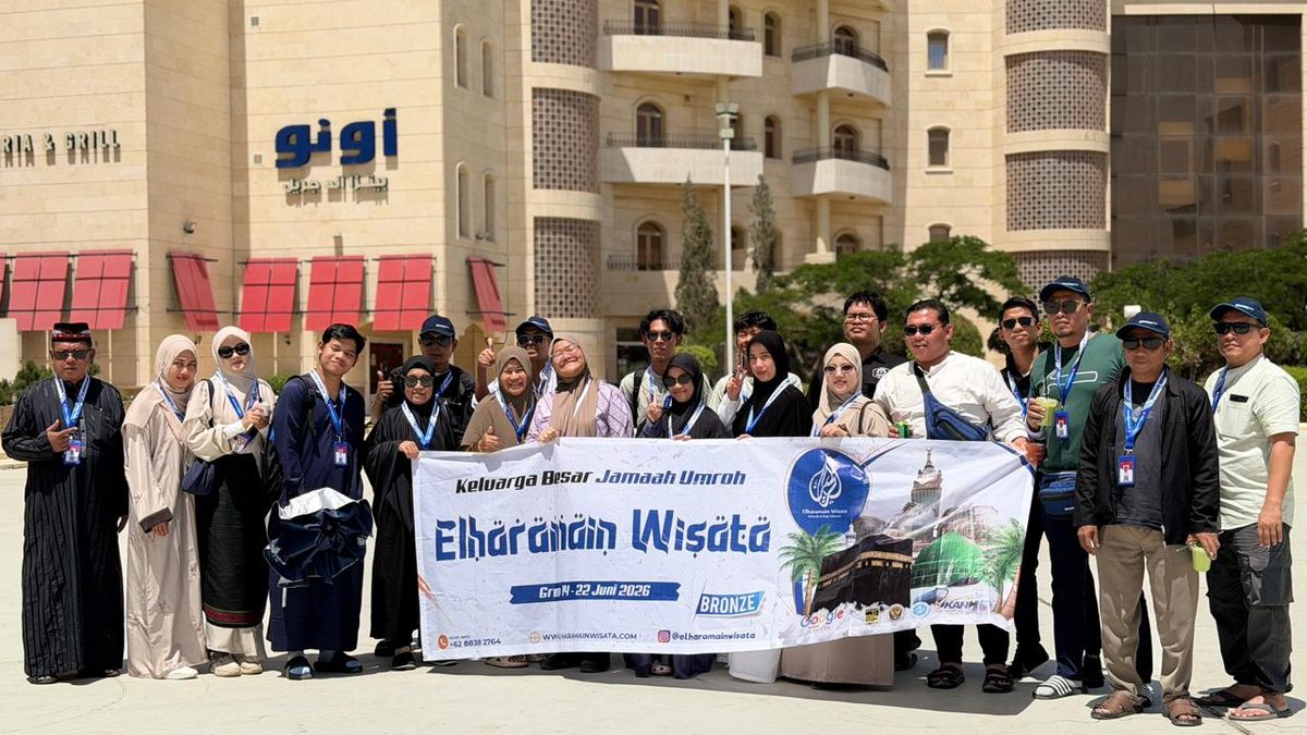 Rombongan jamaah Elharamain Wisata berfoto bersama banner di depan hotel