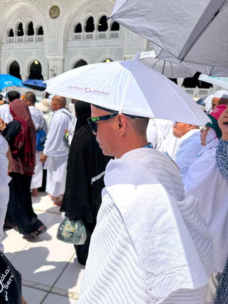Jamaah haji Elharamain Wisata memakai payung kepala di pelataran Masjidil Haram