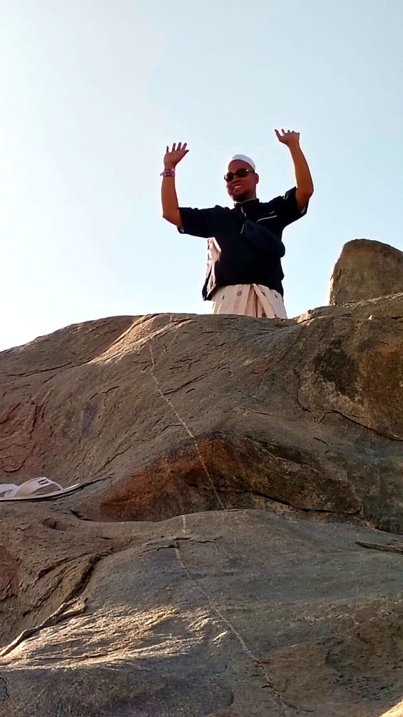 Jamaah haji Elharamain Wisata berdiri di atas bebatuan di kaki Jabal Rahmah
